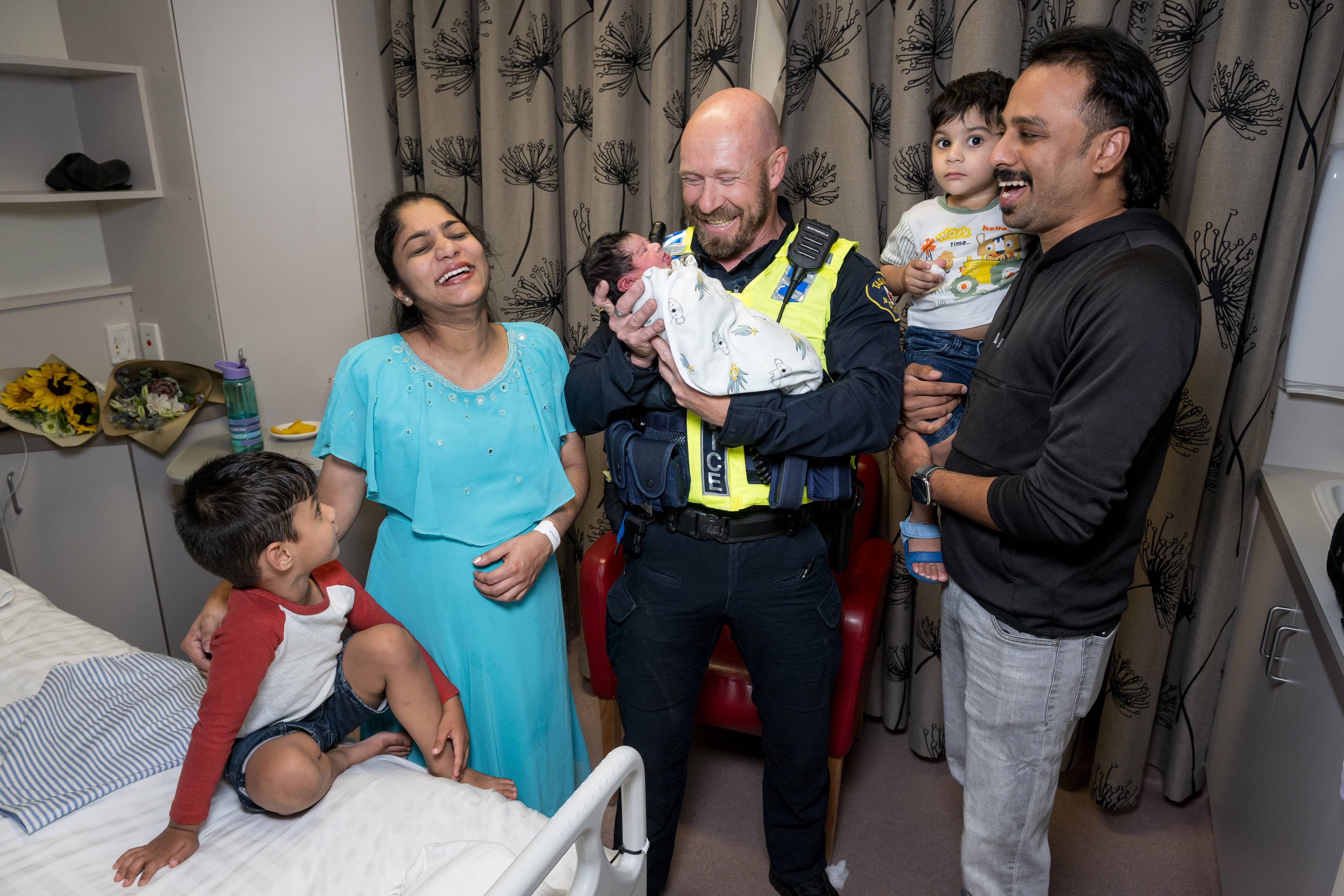 Constable Jason Stone helped mum Jiya James to deliver baby Nahal at the hospital entrance. Pictured, Naithen Paul Bibin, mum Jiya James, Constable Jason Stone, baby Nahal Maria Bibin, Nigel Jim Bibin and dad Bibin Paul.